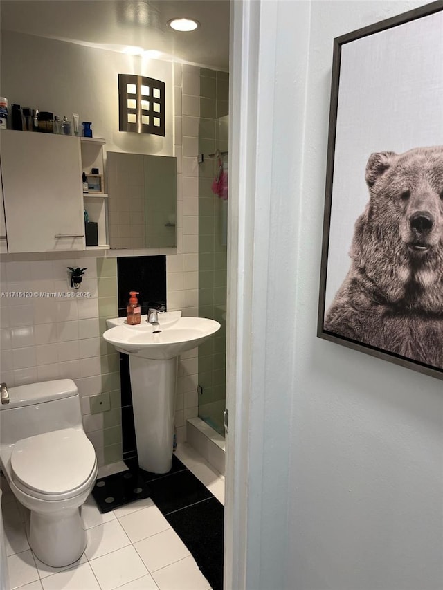 full bath with toilet, tile walls, a shower stall, and tile patterned flooring