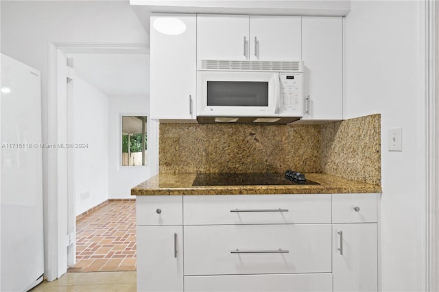 kitchen with tasteful backsplash, dark stone countertops, white cabinets, and white appliances