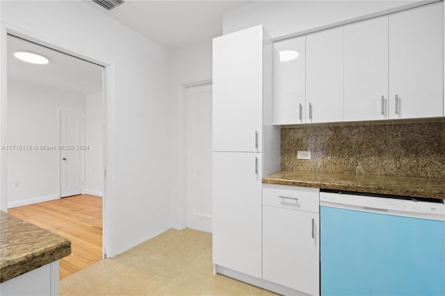 kitchen featuring tasteful backsplash, white cabinetry, dishwasher, and dark stone counters