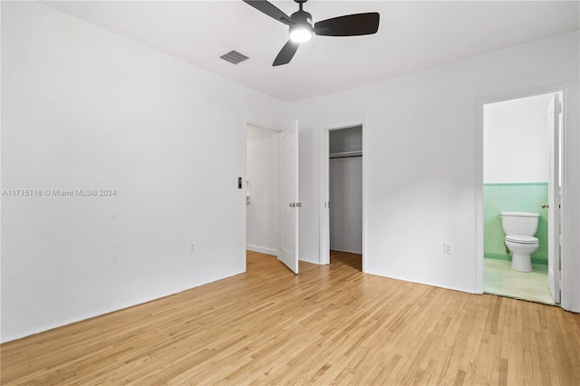 unfurnished bedroom featuring ensuite bath, ceiling fan, light hardwood / wood-style floors, a closet, and tile walls