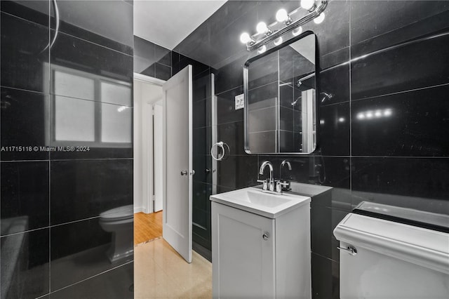 bathroom with tile patterned floors, vanity, tile walls, and toilet