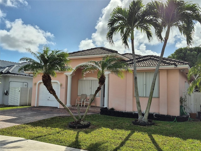 mediterranean / spanish home featuring a garage and a front lawn