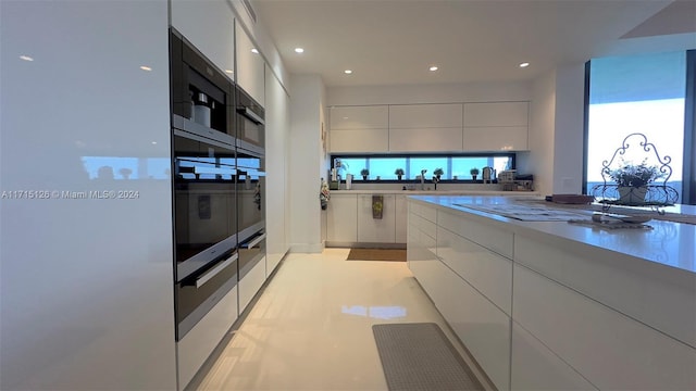 kitchen featuring wall oven, white cabinetry, sink, and light tile patterned floors