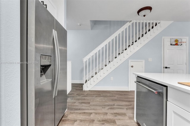 kitchen with white cabinets, appliances with stainless steel finishes, and light hardwood / wood-style flooring