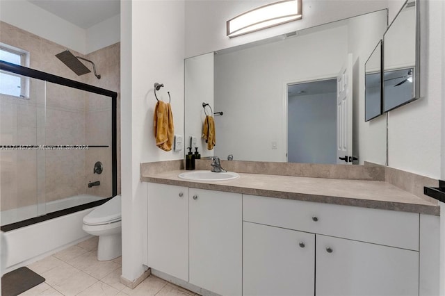 full bathroom with tile patterned floors, vanity, bath / shower combo with glass door, and toilet