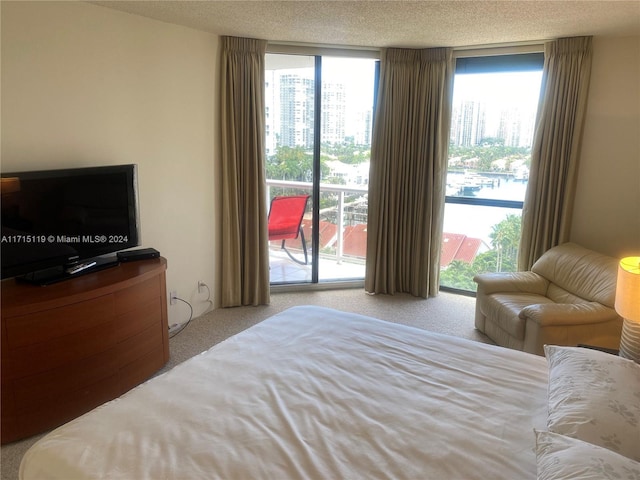 carpeted bedroom with a textured ceiling, access to outside, and a wall of windows