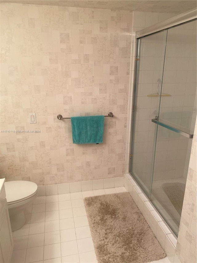 bathroom with tile patterned flooring, toilet, and a shower with shower door