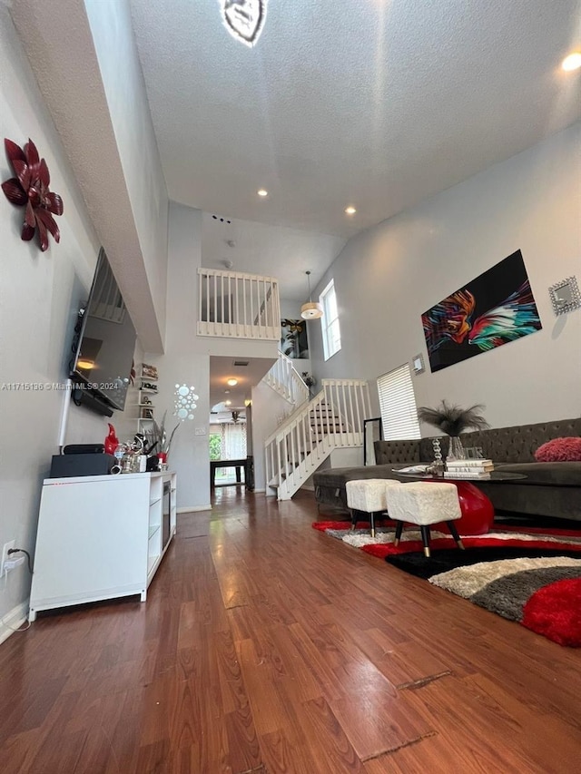 living room with plenty of natural light, dark hardwood / wood-style flooring, a towering ceiling, and a textured ceiling