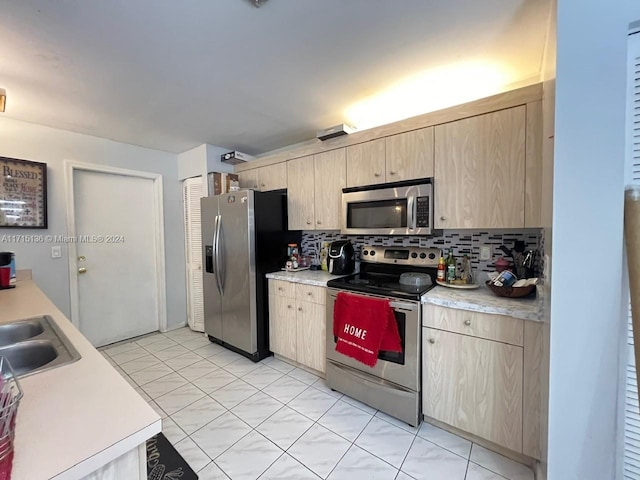 kitchen featuring appliances with stainless steel finishes, tasteful backsplash, light brown cabinetry, and sink