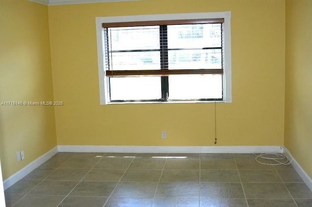 spare room with dark tile patterned flooring and crown molding