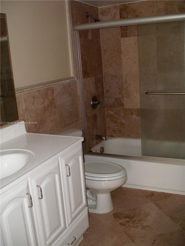 full bathroom with vanity, toilet, tile walls, and tiled shower / bath