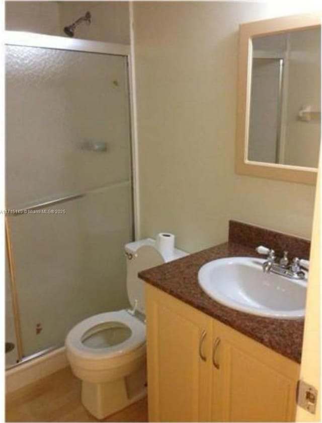 bathroom featuring vanity, toilet, and a shower with door