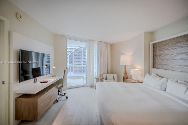 bedroom featuring access to outside, light hardwood / wood-style flooring, and a wall of windows