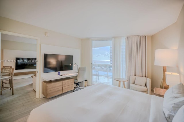 bedroom featuring expansive windows, access to outside, and light hardwood / wood-style flooring