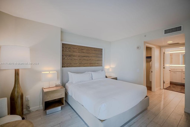 bedroom with ensuite bathroom and light wood-type flooring