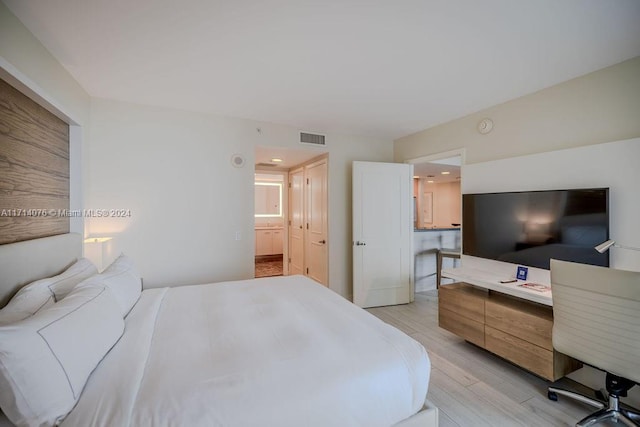 bedroom with ensuite bathroom and light hardwood / wood-style flooring