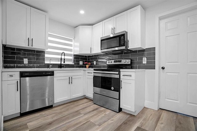 kitchen featuring decorative backsplash, light wood-type flooring, white cabinetry, and appliances with stainless steel finishes