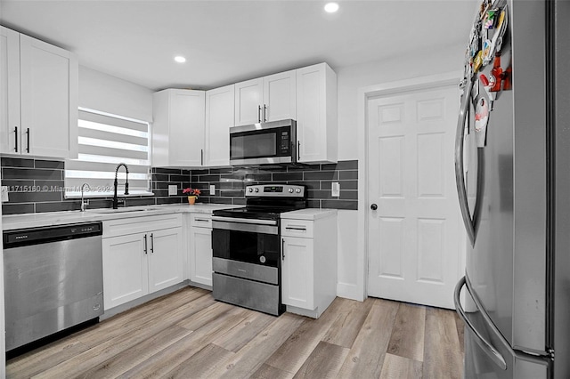 kitchen featuring white cabinets, sink, light wood-type flooring, and stainless steel appliances