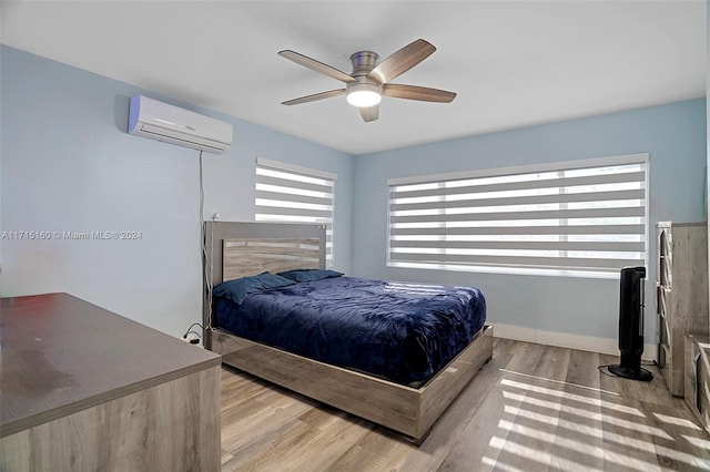 bedroom with ceiling fan, an AC wall unit, and light hardwood / wood-style flooring