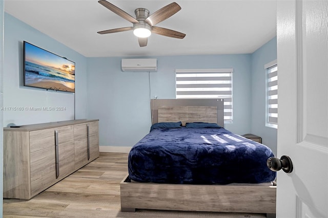 bedroom featuring ceiling fan, light wood-type flooring, and a wall unit AC