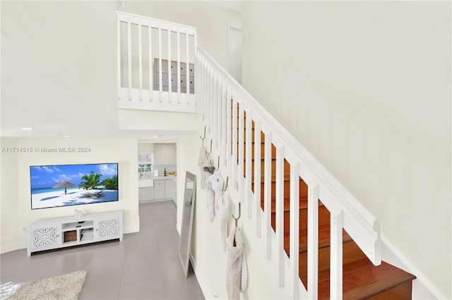 staircase with tile patterned flooring and a towering ceiling