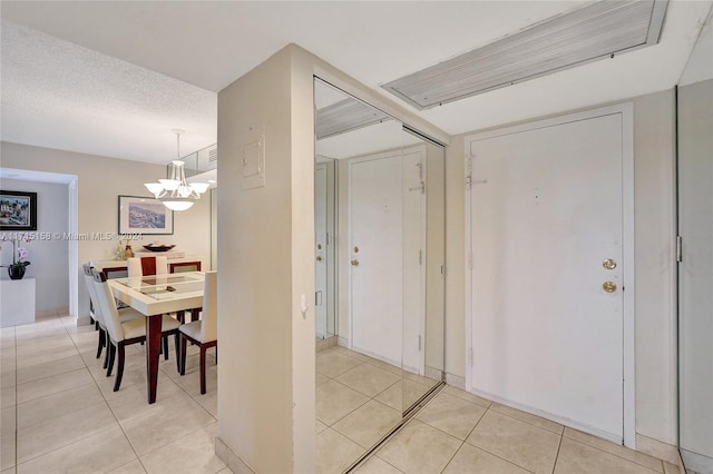 tiled dining room with a textured ceiling and a notable chandelier