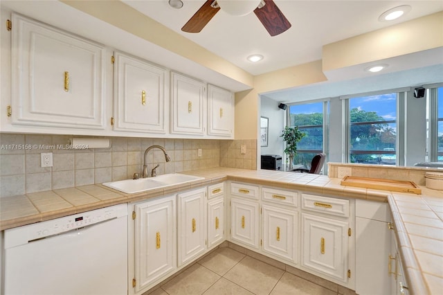 kitchen featuring backsplash, white dishwasher, sink, white cabinetry, and tile counters