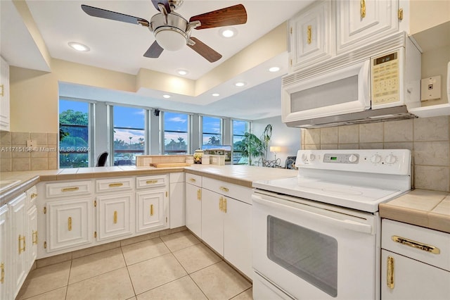 kitchen with light tile patterned floors, white appliances, white cabinetry, and tile counters