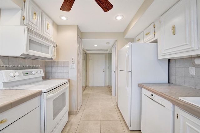 kitchen featuring white appliances, ceiling fan, light tile patterned floors, tile counters, and white cabinetry