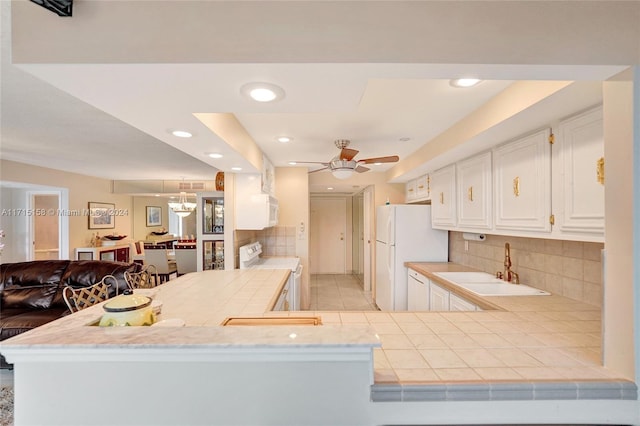 kitchen with white cabinets, sink, white appliances, and kitchen peninsula