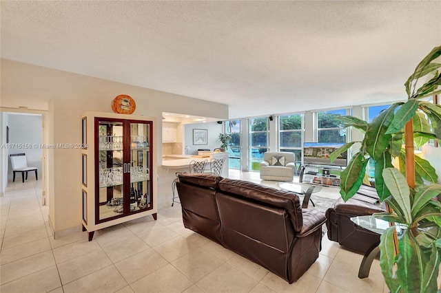 tiled living room with a textured ceiling and a wall of windows