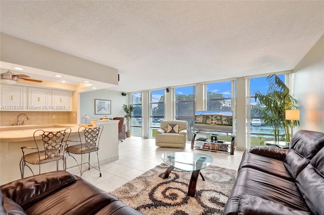 tiled living room featuring a textured ceiling, expansive windows, and ceiling fan