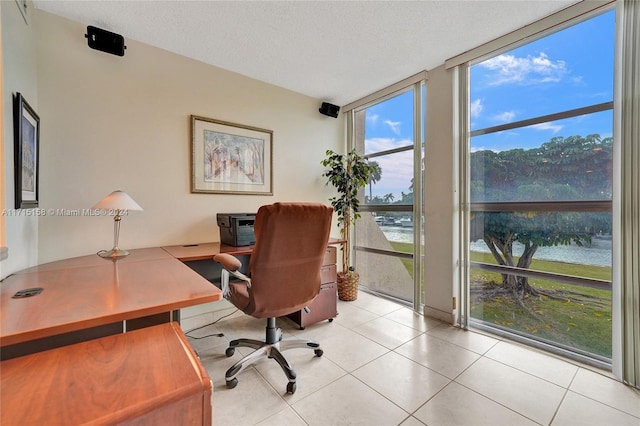 office area featuring a wealth of natural light, a textured ceiling, a water view, and a wall of windows