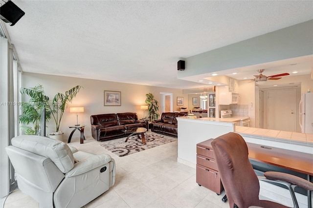 tiled living room with ceiling fan and a textured ceiling