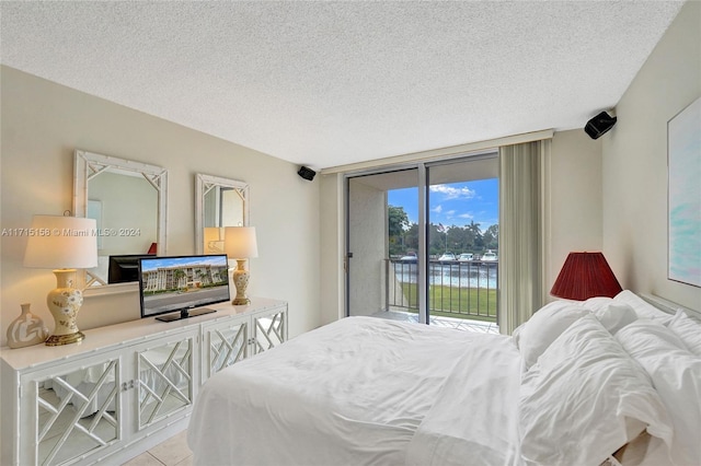 bedroom with floor to ceiling windows, light tile patterned floors, a textured ceiling, and access to outside