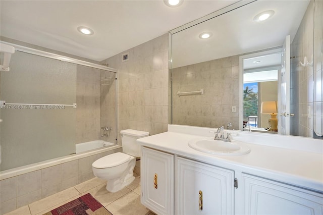 full bathroom featuring vanity, tile patterned floors, bath / shower combo with glass door, toilet, and tile walls