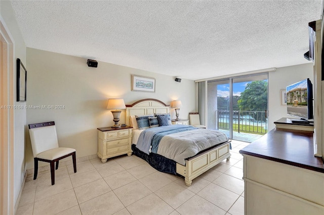 tiled bedroom with a textured ceiling, access to outside, and a wall of windows