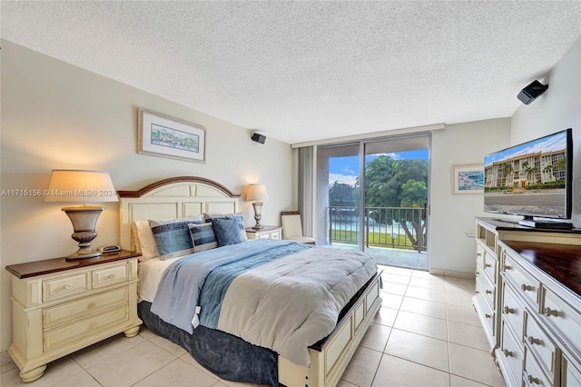 bedroom featuring access to outside, a textured ceiling, expansive windows, and light tile patterned floors