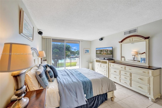 tiled bedroom featuring a textured ceiling, access to outside, and floor to ceiling windows