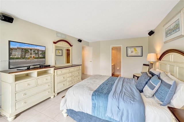 bedroom featuring connected bathroom, light tile patterned flooring, and a textured ceiling