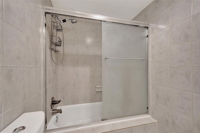 bathroom with toilet, tile walls, and enclosed tub / shower combo