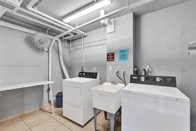 washroom with washer and clothes dryer, light tile patterned floors, and sink