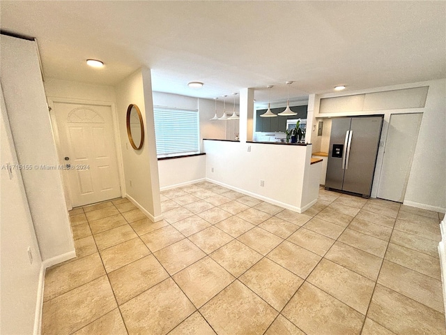 kitchen featuring light tile patterned flooring, stainless steel refrigerator with ice dispenser, hanging light fixtures, and wooden counters