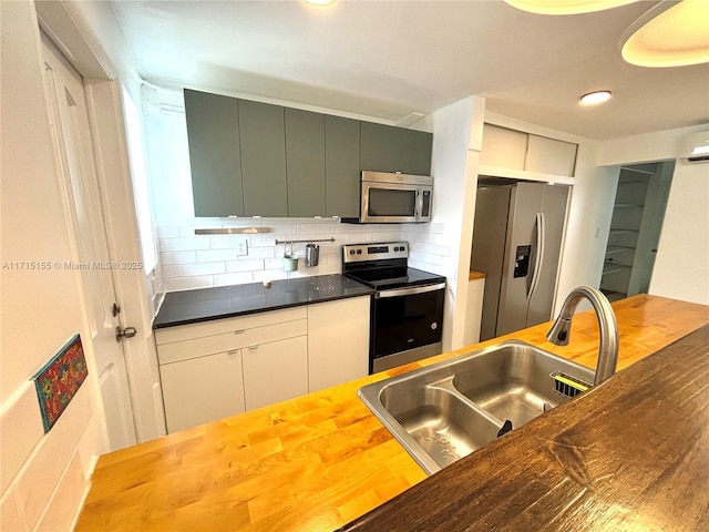 kitchen with stainless steel appliances, a sink, decorative backsplash, and modern cabinets