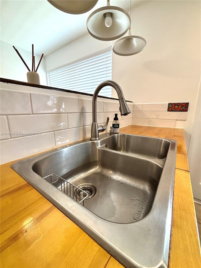 kitchen with wood counters, sink, hanging light fixtures, decorative backsplash, and appliances with stainless steel finishes