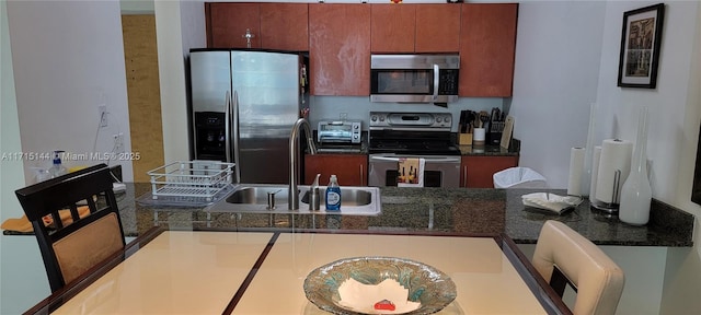 kitchen with stainless steel appliances, dark stone countertops, and sink