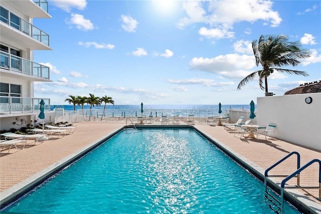 view of pool with a water view and a patio