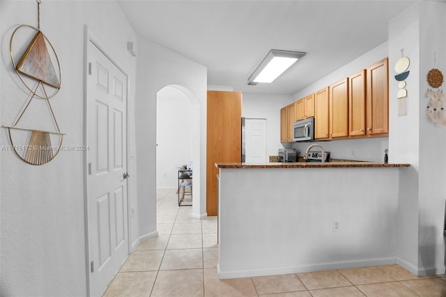 kitchen with light tile patterned floors, kitchen peninsula, and light brown cabinetry