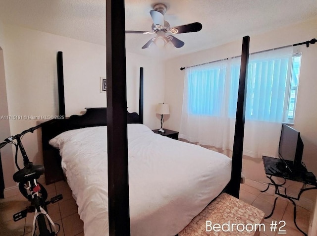 tiled bedroom featuring ceiling fan and a textured ceiling