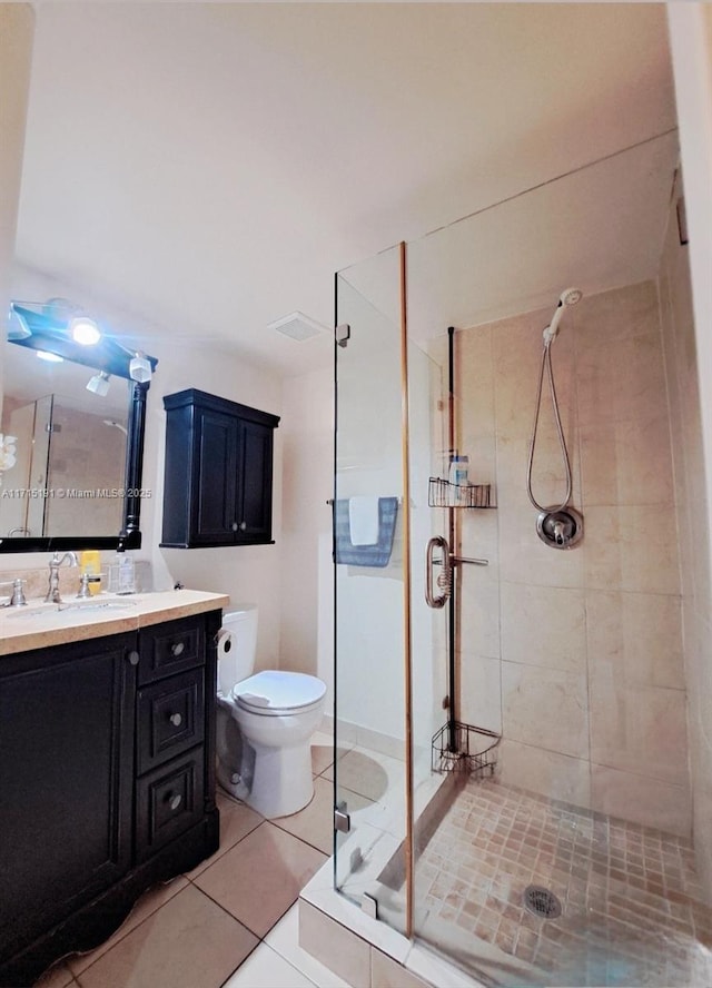 bathroom featuring tile patterned floors, toilet, a shower with door, and vanity